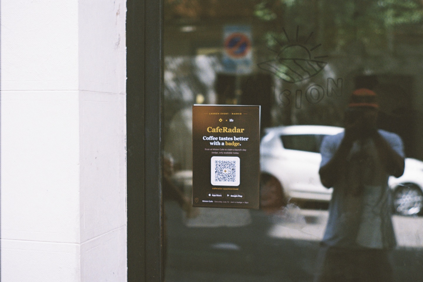 The CafeRadar and ife launch day poster on the glass door of Mision Cafe with the street reflected