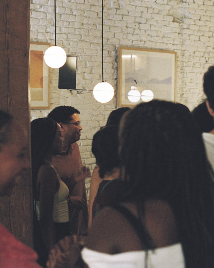 The crowd talking under pendant lights and white brick at Mision Cafe